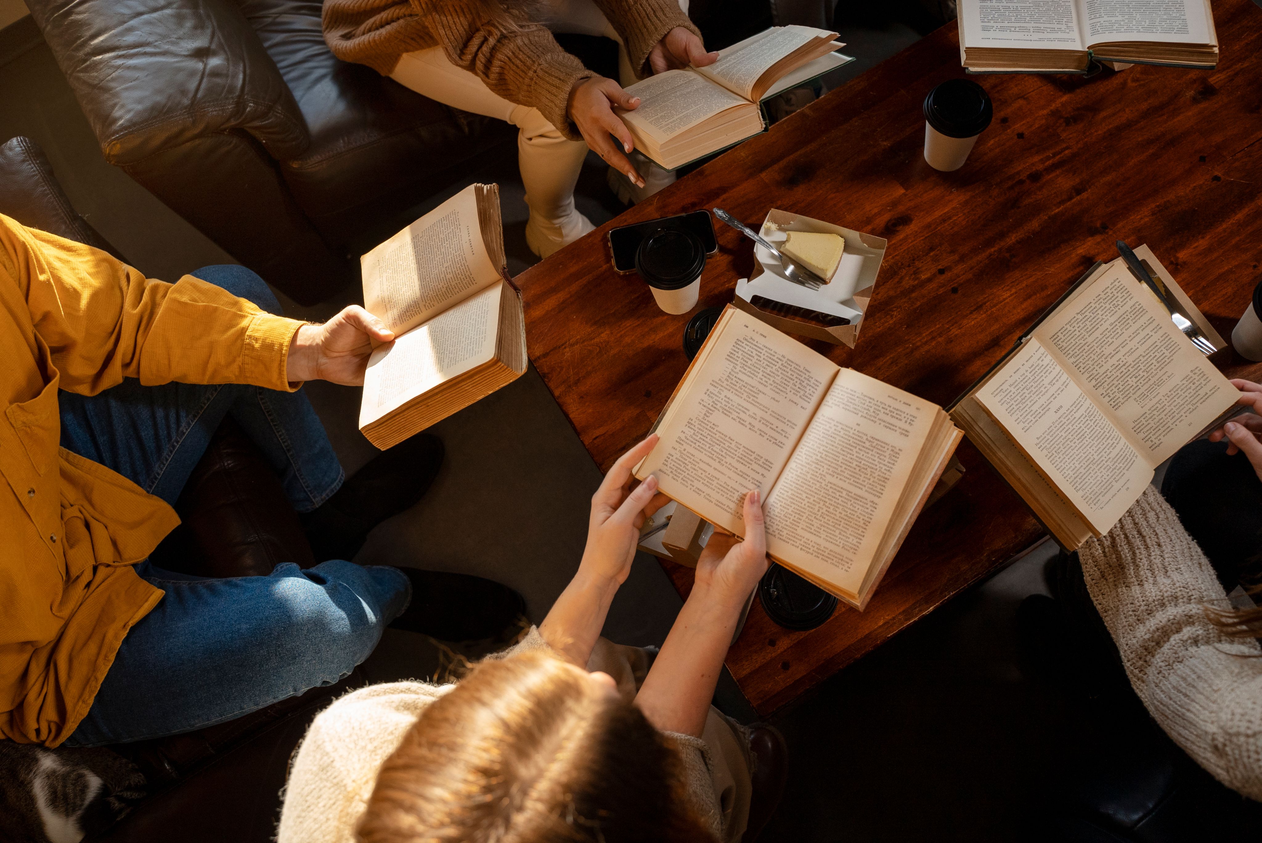 Top down view of a reading group, with a close up shot of all of the students books that they are reading.